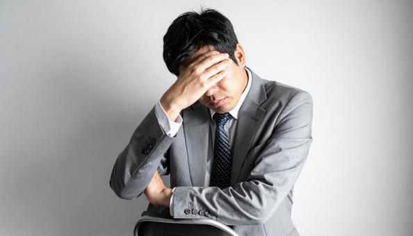 ビジネスイメージ　頭を抱えるビジネスマンの写真