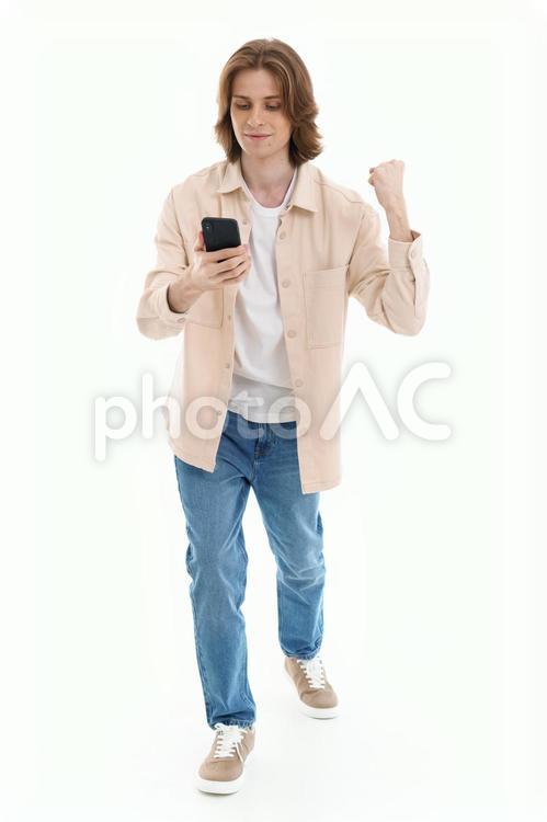 スマホを見てガッツポーズをする外国人男性 男性,スマートフォン,持つの写真素材