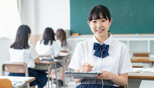 イヤホンをしてタブレットを見る女子学生 イヤホンをしてタブレットを見る女子学生の写真