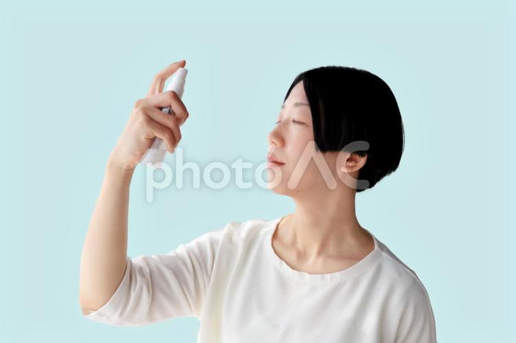 化粧水を顔に吹きかける女性２　水色背景 人物,女性,ライフスタイルの写真素材