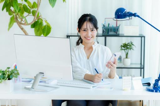 オフィスでスマホを持つビジネスウーマン スマホ,笑顔,ビジネスウーマンの写真素材