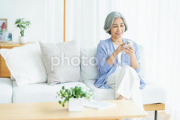 リビングでスマホを操作するシニア女性 シニア,スマホ,笑顔の写真素材