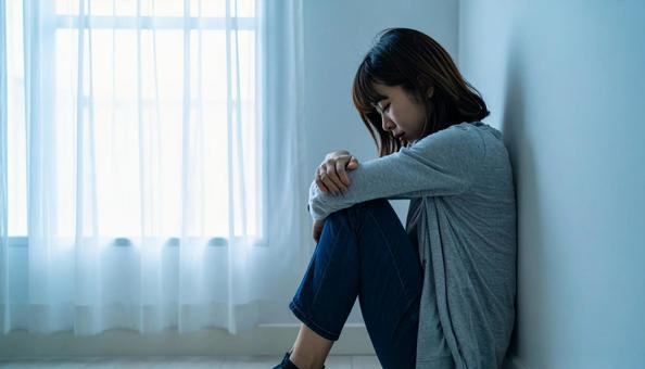 部屋で落ち込んで座る日本人女性の横顔 部屋で落ち込んで座る日本人女性の横顔の写真