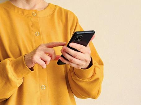スマホを操作する黄色い服の女性 スマホ,女性,操作の写真素材