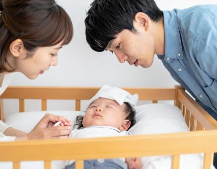 熱を出す赤ちゃんを心配そうに見守る夫婦 熱を出す赤ちゃんを心配そうに見守る夫婦の写真