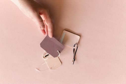 茶色いタグを持っている手(ピンク背景) 茶色いタグを持っている手(ピンク背景) モックアップ,女性,手の写真素材