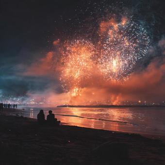 夜の海に映る鮮やかな花火と夏祭りの情景の写真