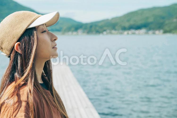 湖の桟橋に立つ女性キャンパーの横顔 キャンプ,湖,女性の写真素材