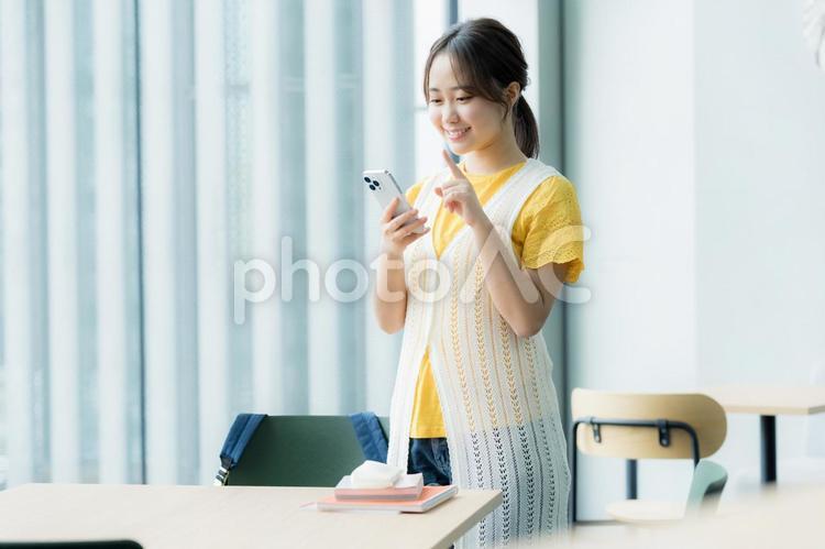 カフェでスマホを見る学生 スマホ,若い女性,笑顔の写真素材