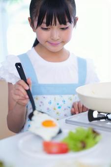 目玉焼きをお皿に盛り付ける女の子 女の子,目玉焼き,フライ返しの写真素材