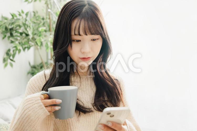 ソファーでくつろぐ若い女性 女性,スマートフォン,ライフスタイルの写真素材