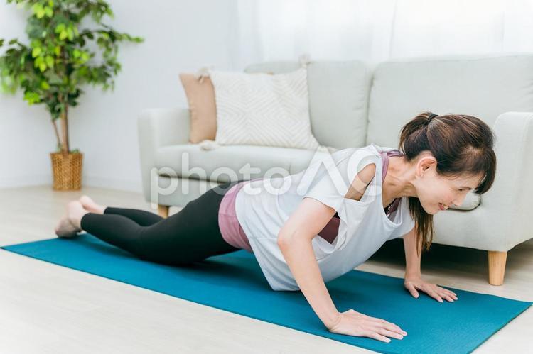 部屋で腕立て伏せをするミドル世代の女性 腕立て伏せ,腕立て,筋トレの写真素材