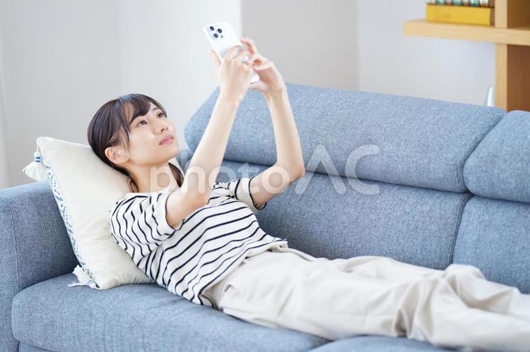 足を伸ばし座りスマートフォンを見ている女性 女性,スマートフォン,持つの写真素材