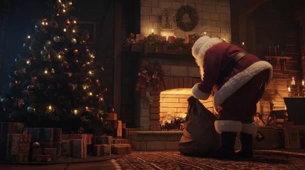 暖炉の前でプレゼントを置くサンタクロースの写真