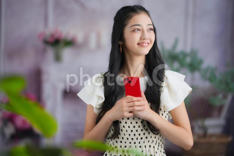スマホを持ち振り向く女性 女性,スマホ,持つの写真素材