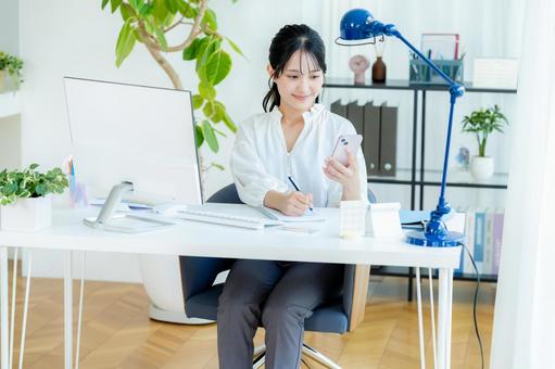 オフィスでスマホを持つビジネスウーマン スマホ,笑顔,ビジネスウーマンの写真素材