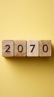 2070年を刻んだ木製ブロックと黄色背景 2070年を刻んだ木製ブロックと黄色背景の写真