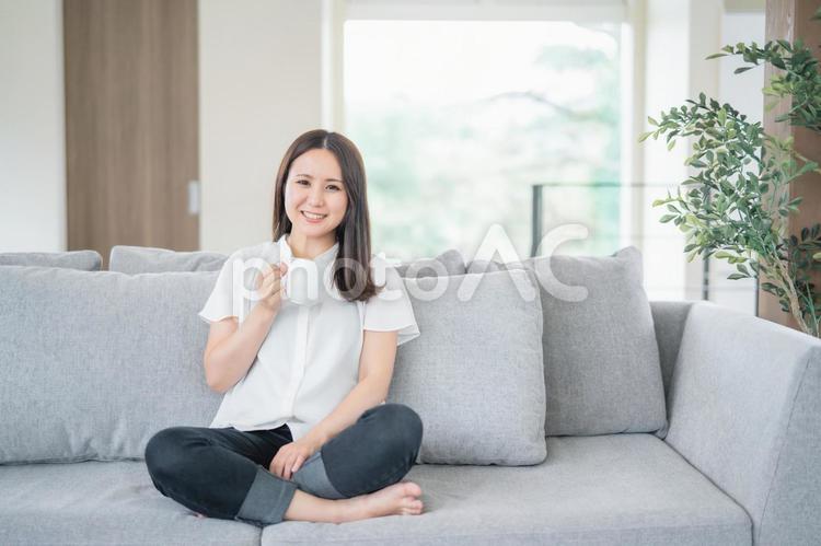 部屋で飲み物を飲む女性（カメラ目線） リラックス,女性,コーヒーの写真素材