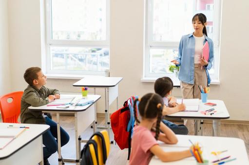 立って教える先生と勉強する生徒たち 女性,女の子,男の子の写真素材