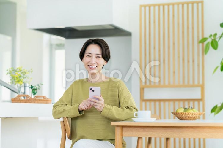 家でスマホを使うミドルの女性 スマートフォン,女性,主婦の写真素材