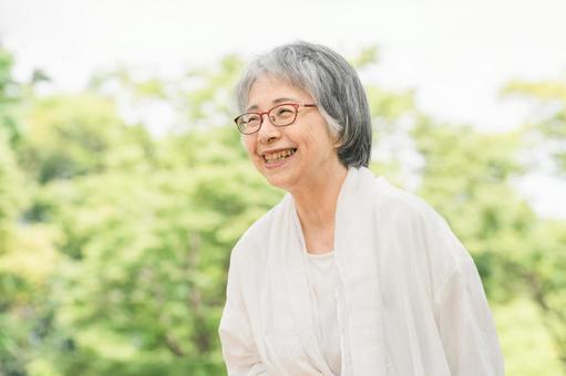 新緑の公園にいる笑顔のシニア女性 シニア,女性,高齢者の写真素材