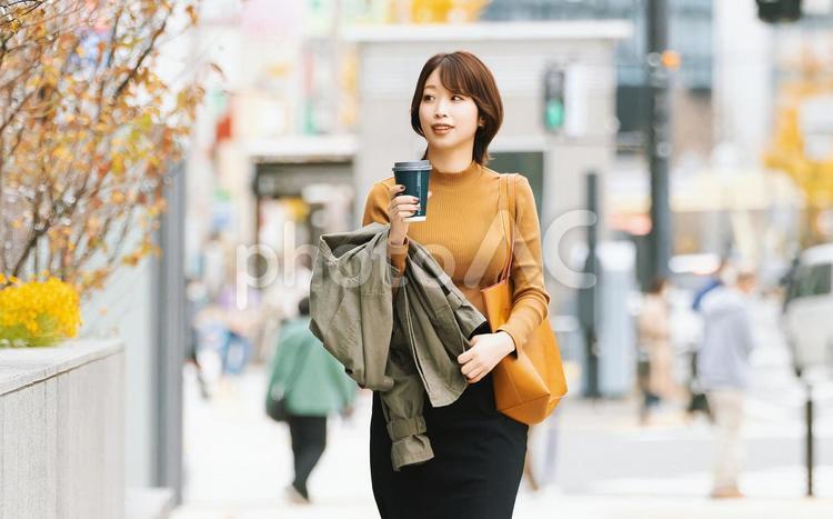 秋のオフィス街を歩く笑顔の女性 女性,秋,ビジネスの写真素材