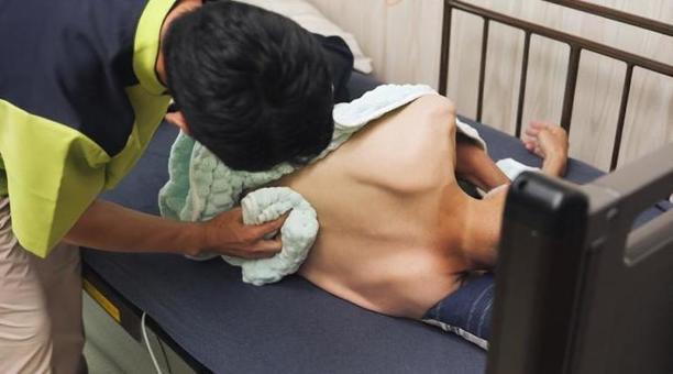 高齢者の清拭を行うアジア人介護士 高齢者の清拭を行うアジア人介護士の写真