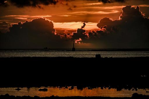 <素材>海に沈む夕日と沖の灯台の風景 <素材>海に沈む夕日と沖の灯台の風景の写真
