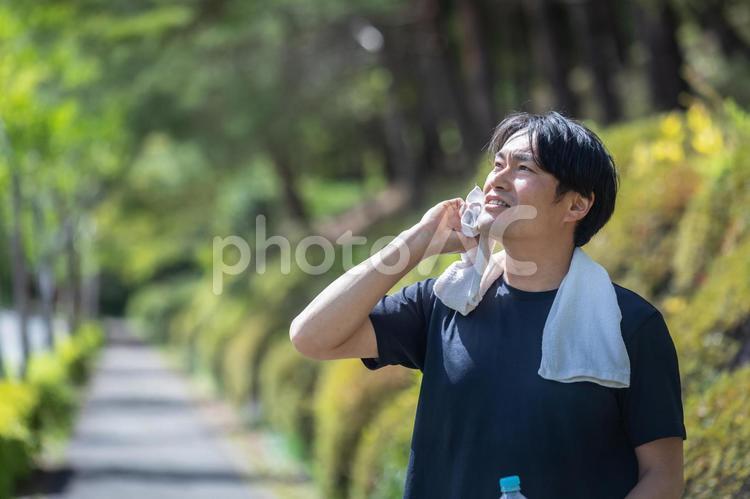 緑の中でウォーキングする男性（汗） 新陳代謝,運動,汗の写真素材