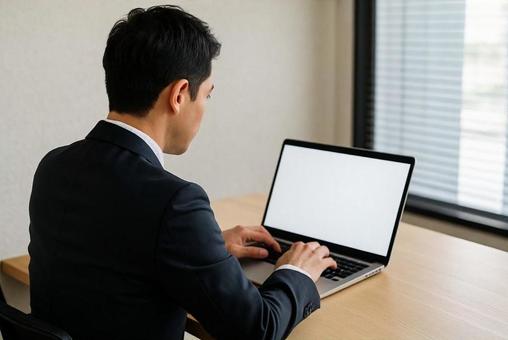 パソコンで仕事するスーツ姿の男性の後ろ姿 パソコンで仕事するスーツ姿の男性の後ろ姿の写真