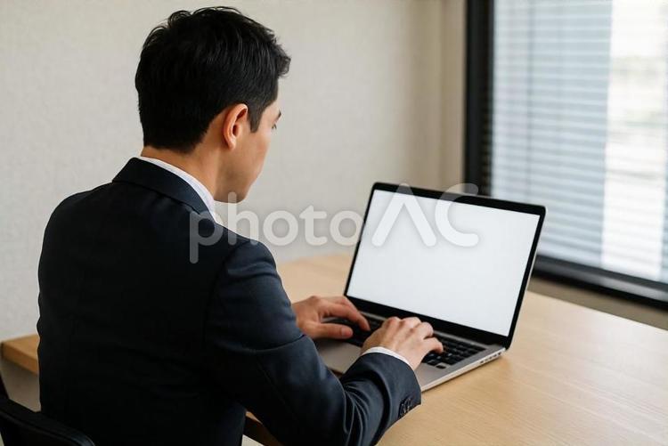 パソコンで仕事するスーツ姿の男性の後ろ姿 ビジネスマン,テレワーク,オフィスの写真素材