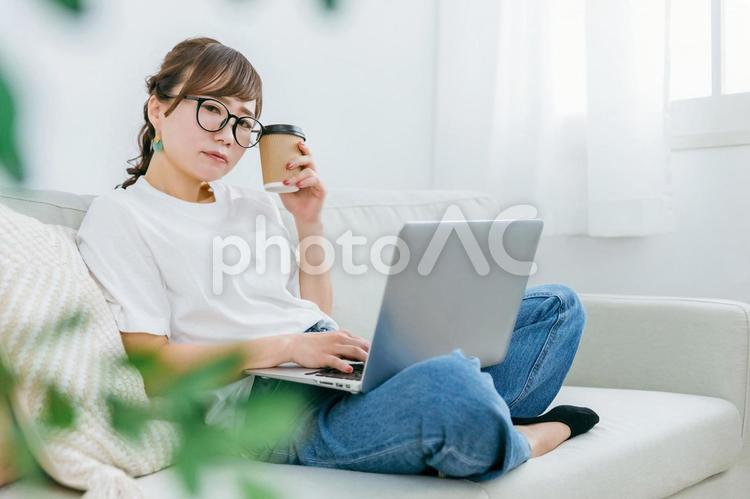 コーヒーを飲みながらパソコンを使う女性 パソコン,女性,困るの写真素材