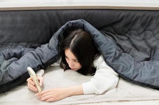 こたつでスマホを触る女性 こたつ,スマホ,スマートフォンの写真素材