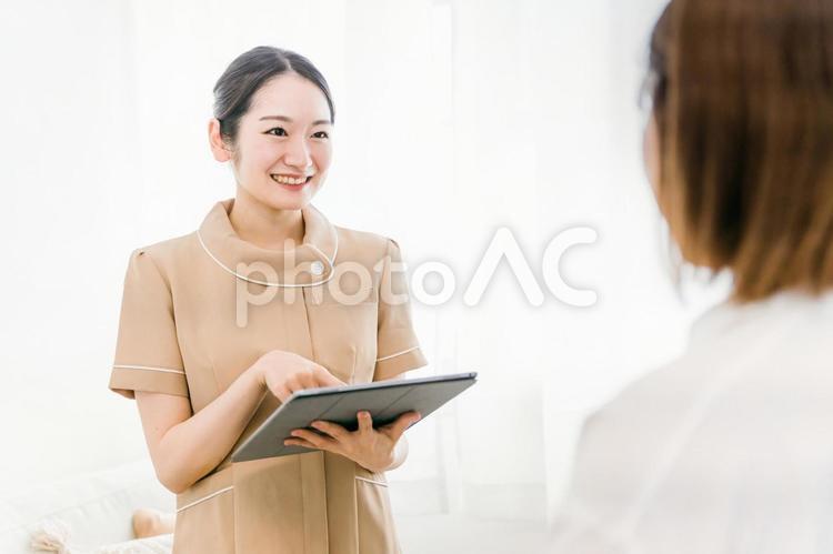 受付で説明をする女性（タブレットPC） 受付,エステサロン,ネイルサロンの写真素材