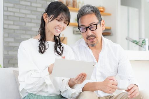 リビングでタブレットを見るミドルの夫婦 リビングでタブレットを見るミドルの夫婦 夫婦,家族,ミドルの写真素材
