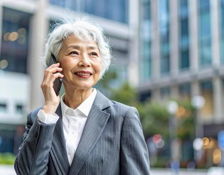 街中で電話をかけるシニアの女性の写真