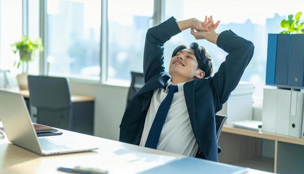 仕事が終わり達成感で背伸びをする社員 仕事が終わり達成感で背伸びをする社員の写真