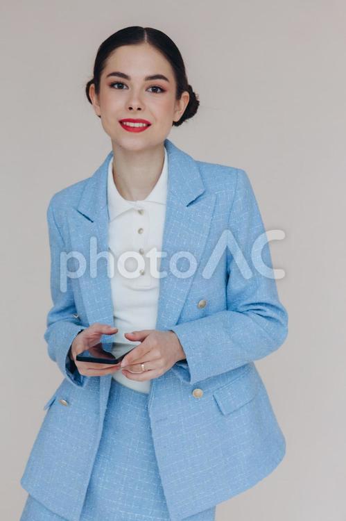 携帯を持って笑顔でスーツの女性 女性,携帯,スマートフォンの写真素材