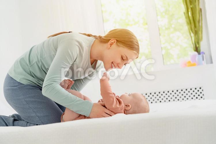 仰向けの赤ちゃんに笑顔で語りかける女性 親子,母子,赤ちゃんの写真素材