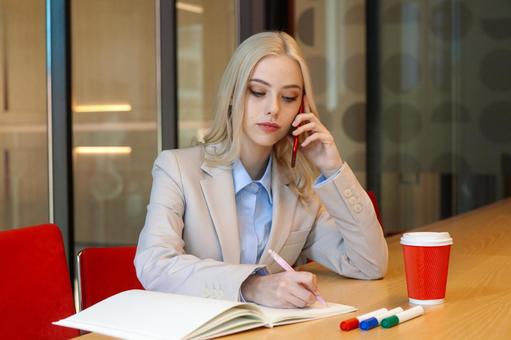 ノートにメモを取りながら電話するビジネスウーマン ビジネスウーマン,ビジネス,女性の写真素材