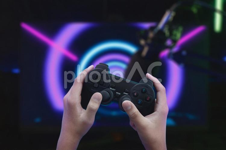 パソコン画面の上でコントローラーを操作する人の手元 手元,人物,コントローラーの写真素材