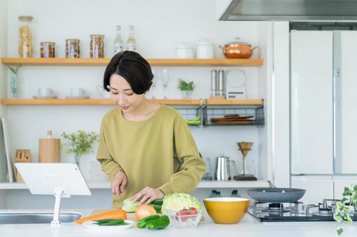 キッチンで調理するミドルの女性 キッチンで調理するミドルの女性の写真