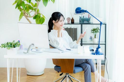 オフィスでスマホを持つビジネスウーマン スマホ,笑顔,ビジネスウーマンの写真素材