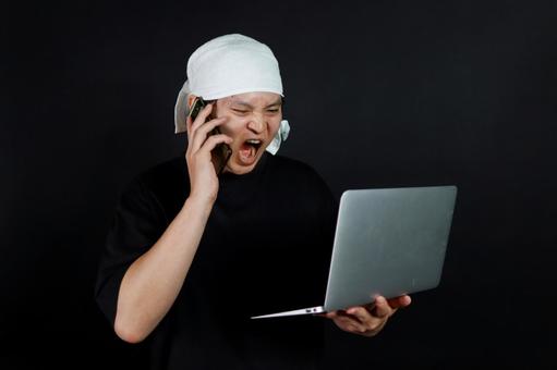 パソコンで怒る若者 パソコンで怒る若者の写真