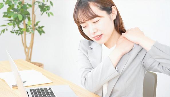 デスクワーク中に肩こりに悩む女性社員の写真
