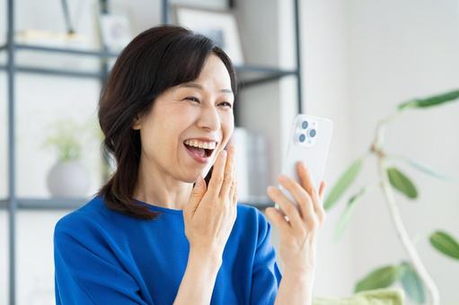 リビングでスマホを見るミドルの女性 リビングでスマホを見るミドルの女性 スマホ,女性,ミドルの写真素材