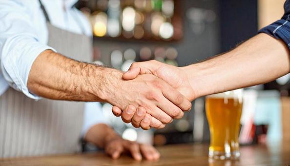 パブで握手してあいさつする外国人男性二人の写真