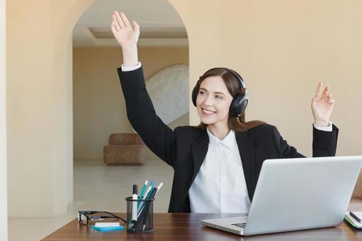 片手をあげ笑顔のヘッドホンの女性 女性,外国人,ノートパソコンの写真素材