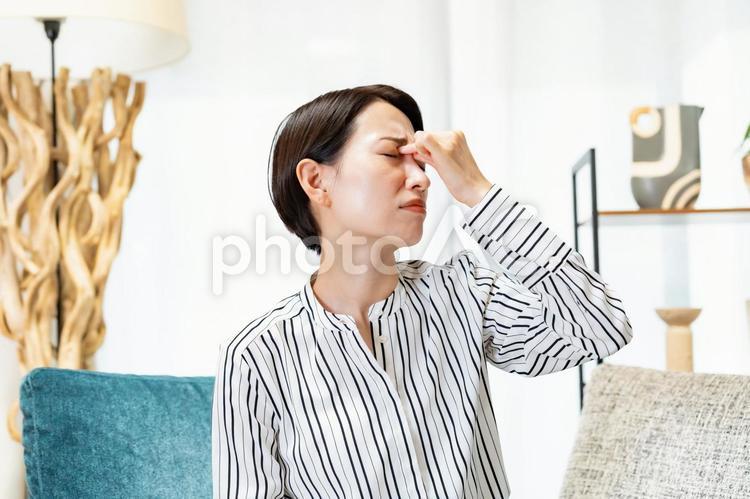 目頭をおさえる女性 頭痛,女性,偏頭痛の写真素材