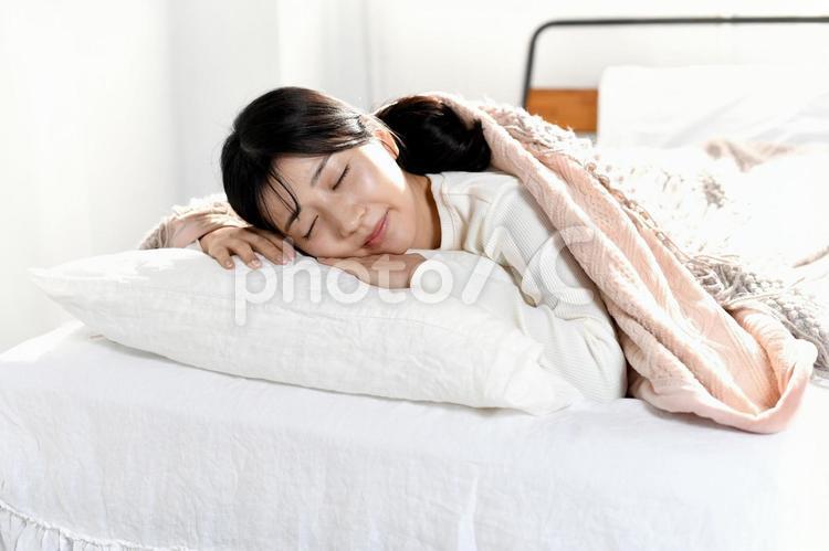 ベッドでうつ伏せで寝るアジア人の若い女性 睡眠,ベッド,女性の写真素材